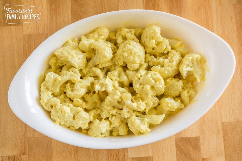 Cauliflower florets coated with sauce in an oval baking dish