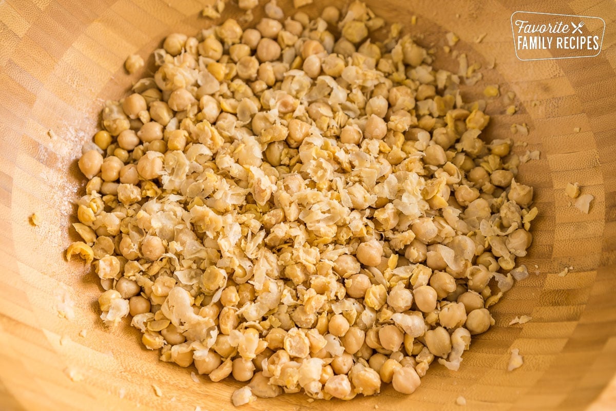 Lightly mashed chickpeas in a large wooden bowl.