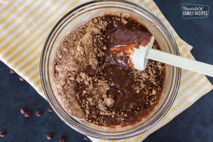 Dry and wet chocolate ingredients folded together in a bowl.