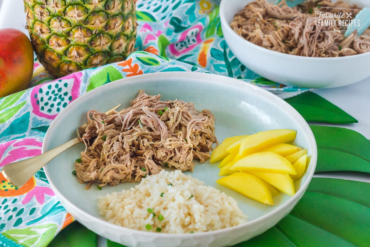 Kalua Pork, mango and rice on a dinner plate.