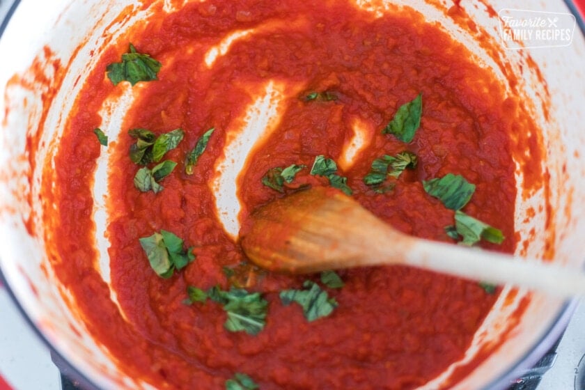 Cooked marinara in a Dutch oven sprinkled with fresh basil