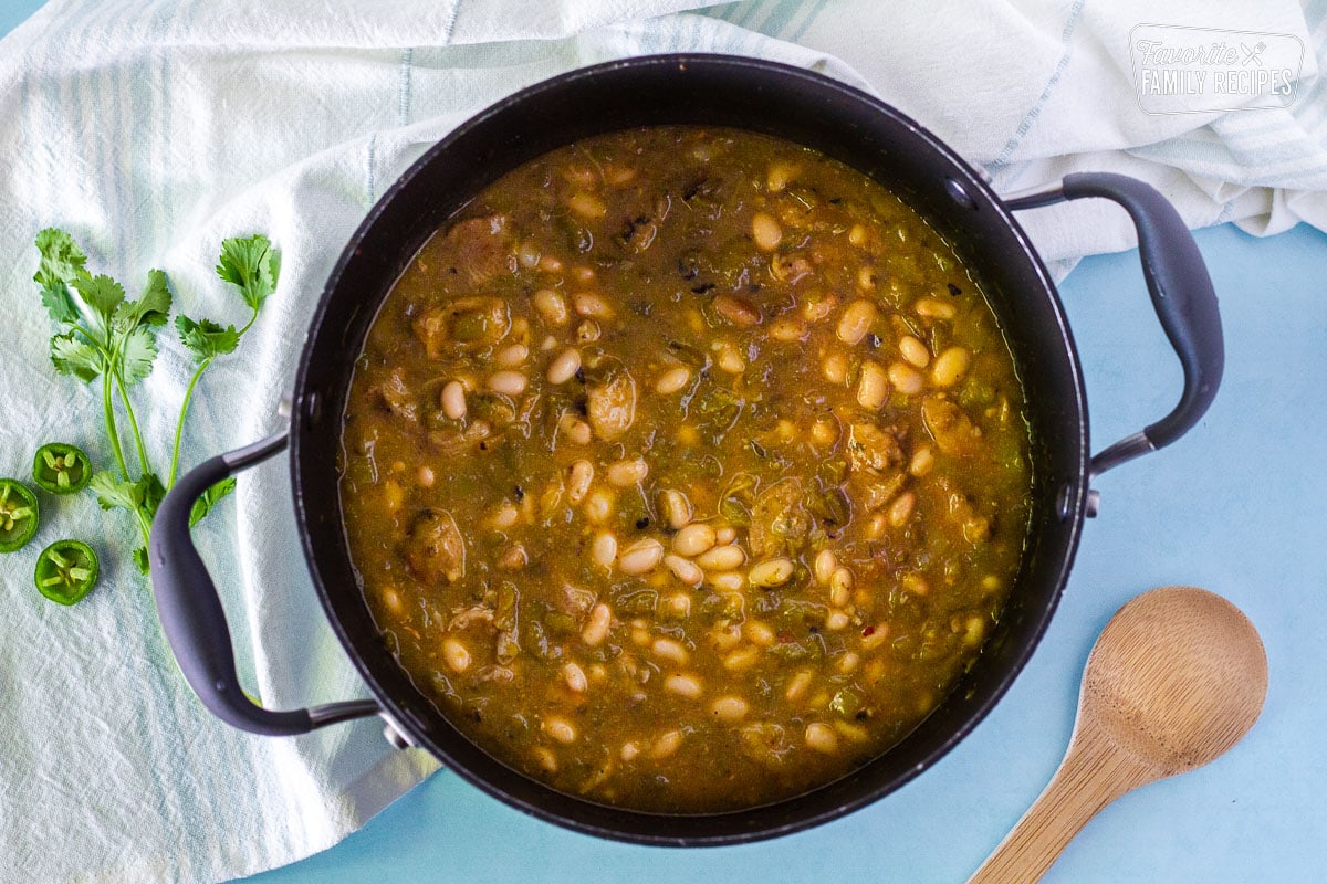 Completed pot of warm Pork Chile Verde with a wooden spoon on the side.