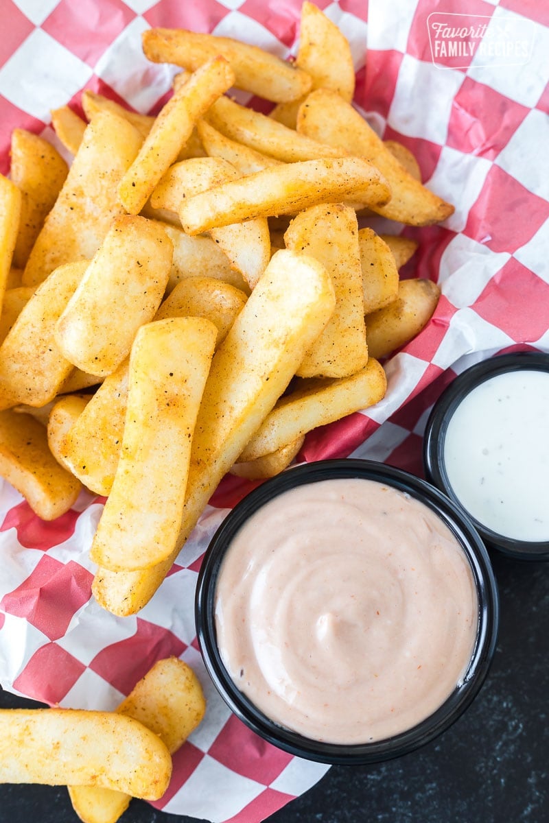 A basket of steak fries next to a cup of campfire sauce.