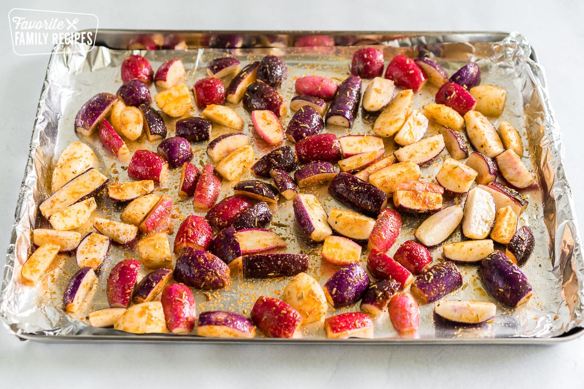 Chopped radishes tossed in olive oil and spices on a large baking sheet