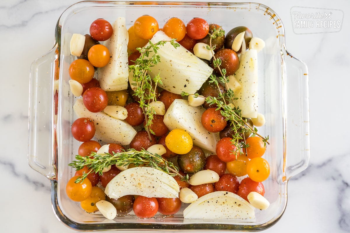 Heirloom cherry tomatoes, onion, garlic, and thyme in a glass baking dish