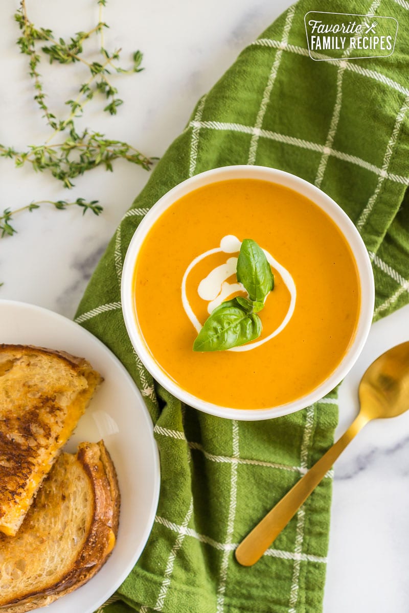 Roasted Tomato Soup in a bowl topped with cream and a basil leaf.