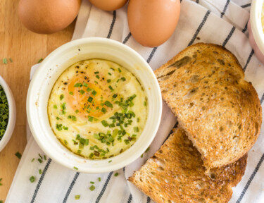 Shirred Eggs in a ramekin with toast next to it