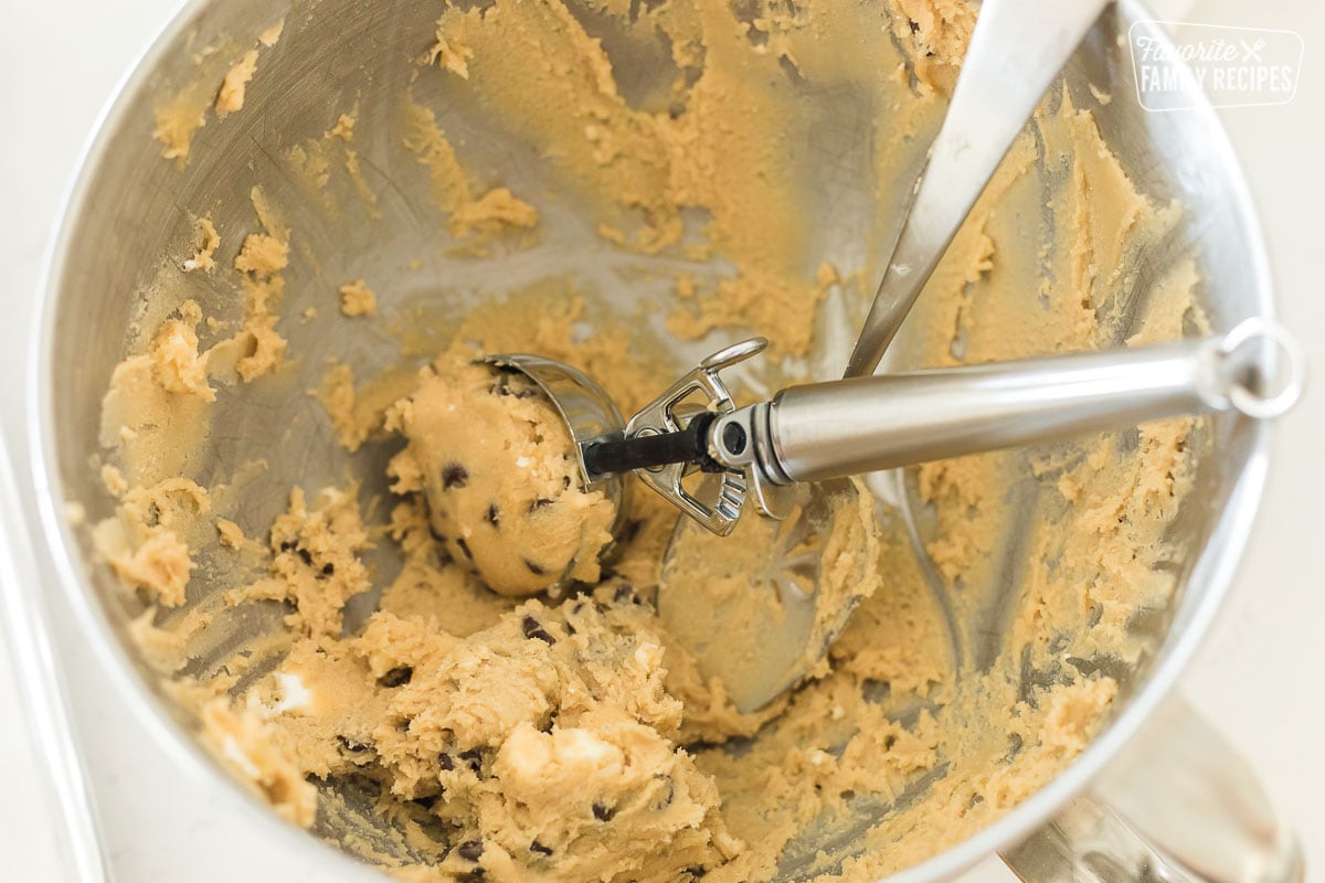 A bowl of cookie dough with an ice cream scoop in it
