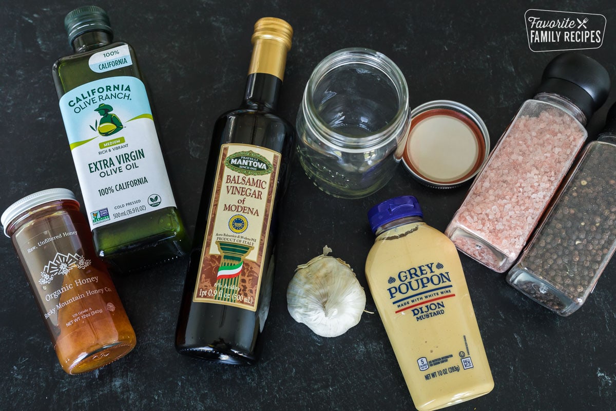 Ingredients to make balsamic vinaigrette including olive oil, vinegar, garlic, mustard, and salt and pepper