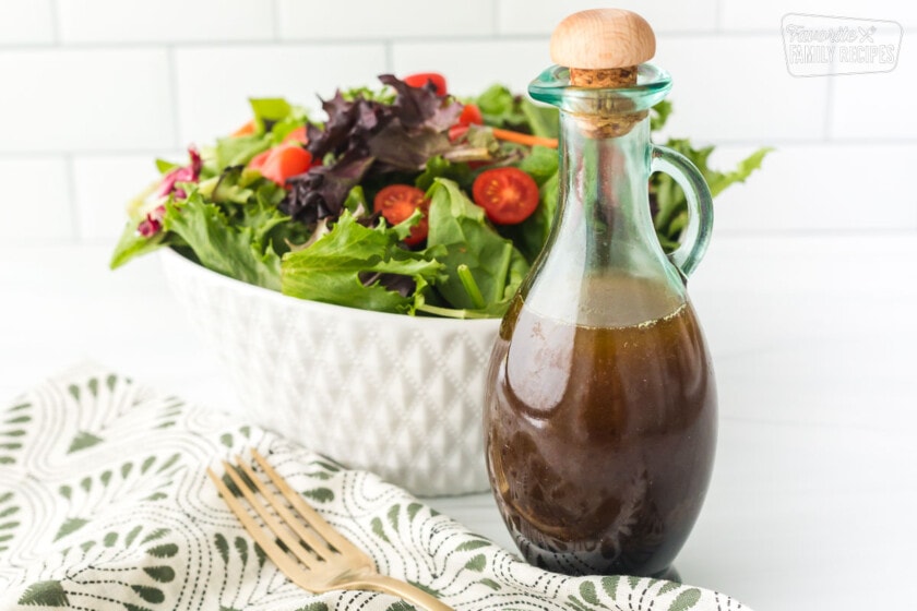 Balsamic vinaigrette in a glass bottle next to a salad