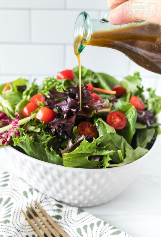 Balsamic vinaigrette being poured over a green salad