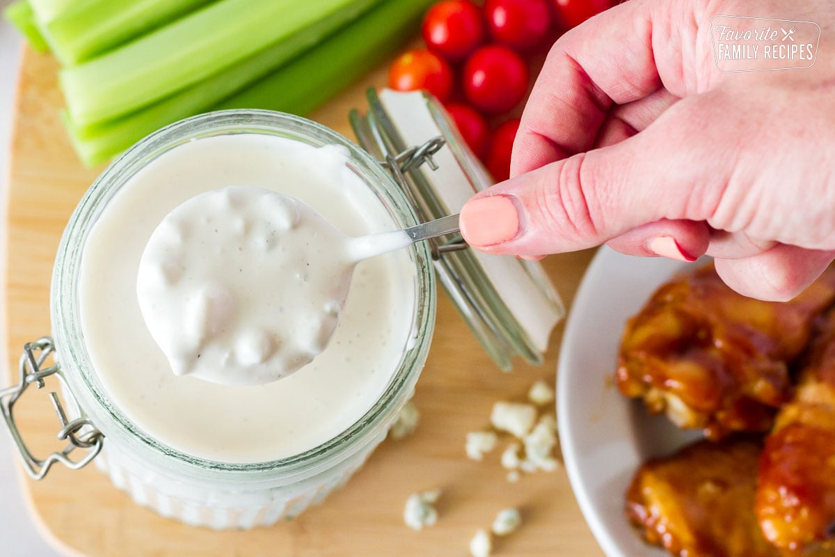 Hand holding spoon full of freshly made Blue Cheese Dressing for Hot Wings.