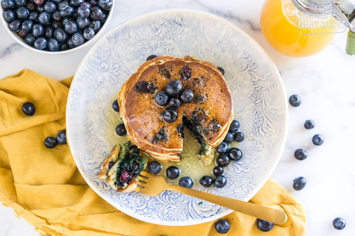 Blueberry pancakes on a plate with a bite cut out.