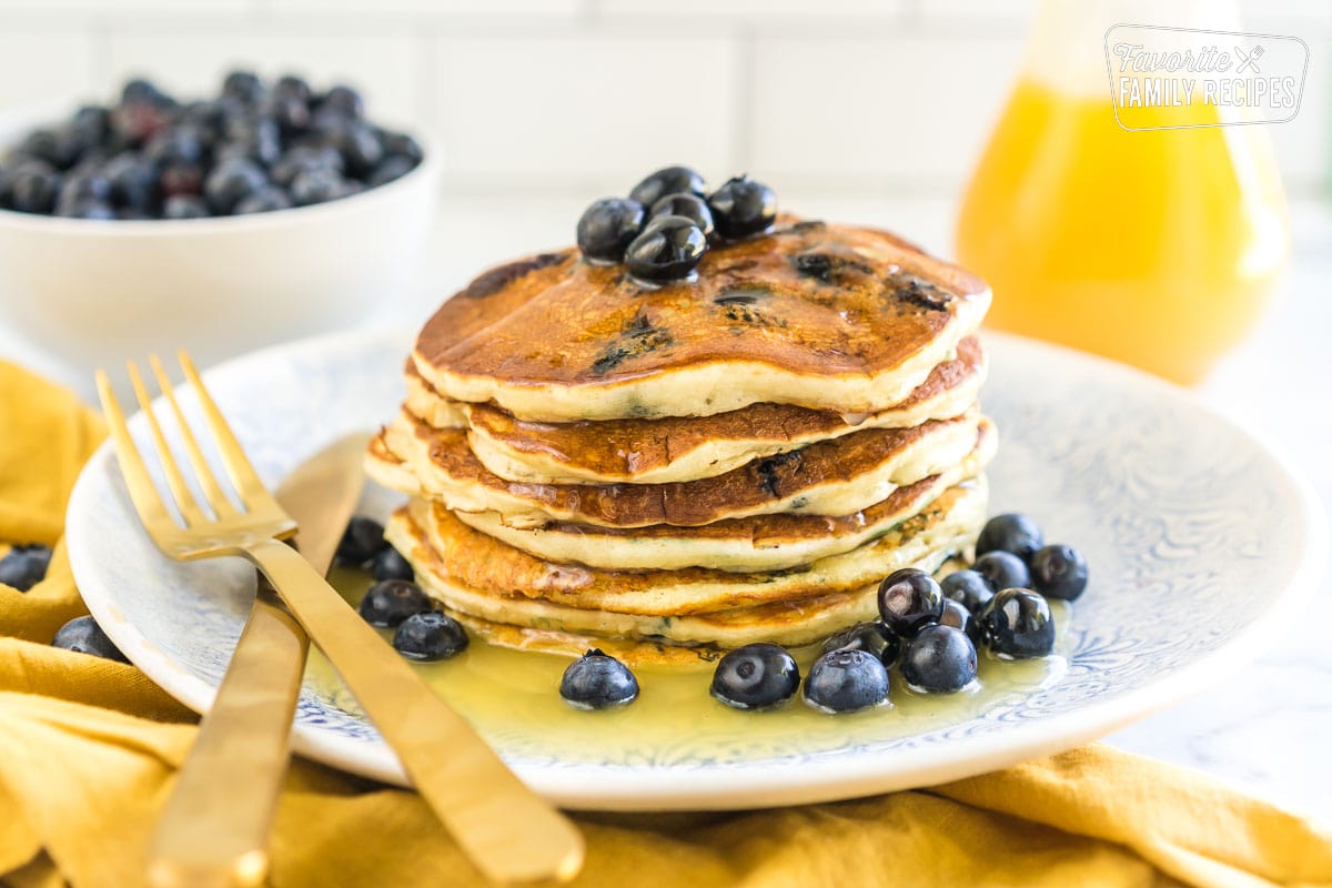 A stack of blueberry pancakes on a plate covered in syrup