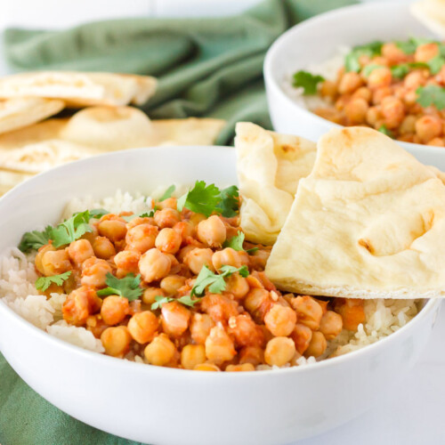 Bowls of Curried Chickpeas over rice with sliced Naan Bread.