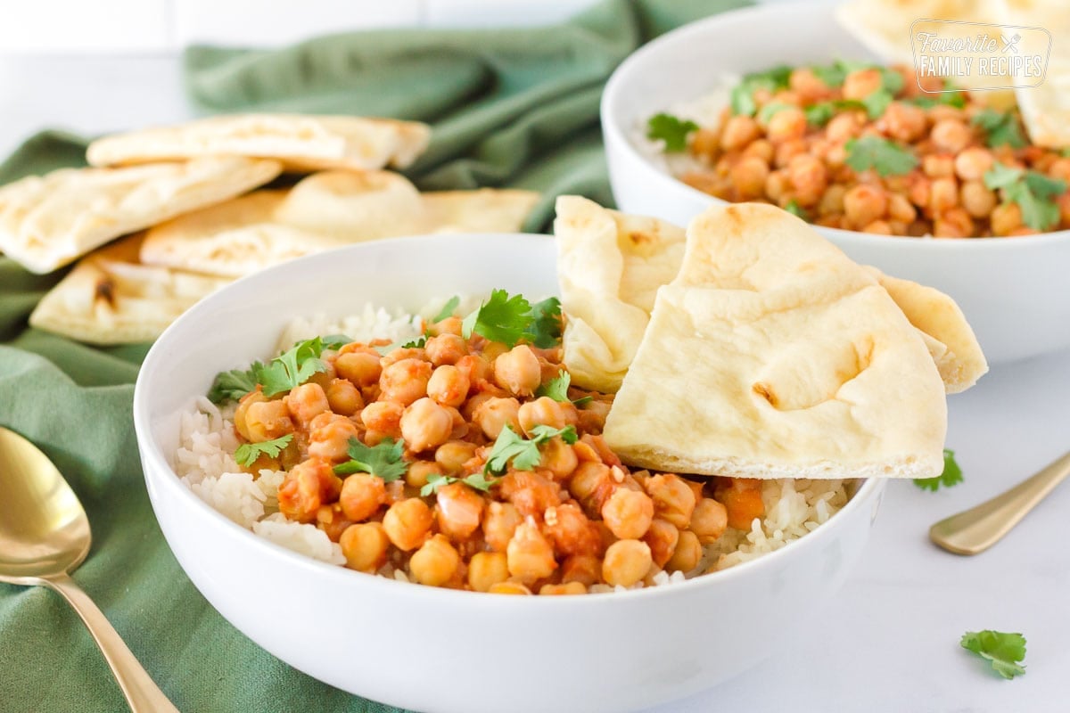 Bowls of Curried Chickpeas over rice with sliced Naan Bread.