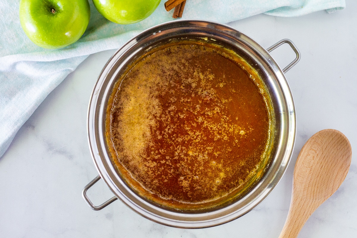 Cooked sugar with butter in a heavy pan and wooden spoon to make the Salted Caramel for Apple Cheesecake Bars.