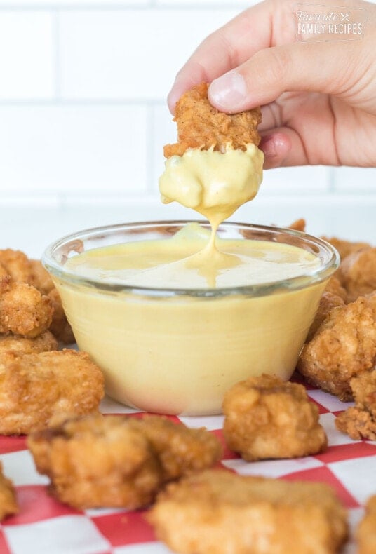 A chicken nugget slowly being dipped into homemade chick-fil-a sauce recipe