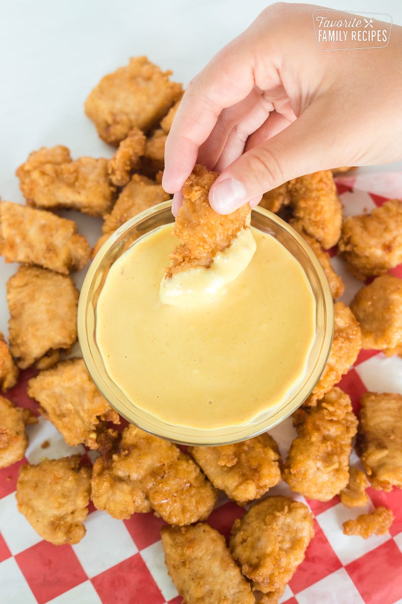 Chick-fil-A sauce with chicken nugget being dipped into sauce.