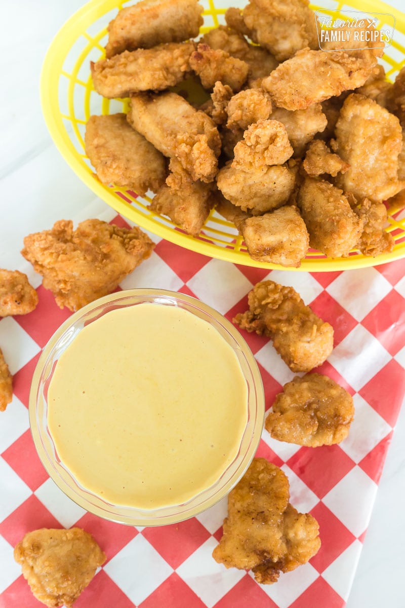 A bowl of Chick-Fil-A sauce next to a basket of chicken nuggets.