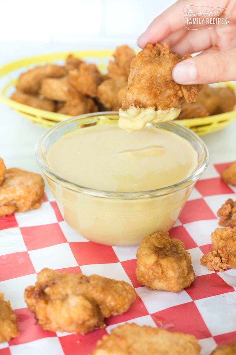 A breaded chicken nugget being dipped into chick-fil-a sauce