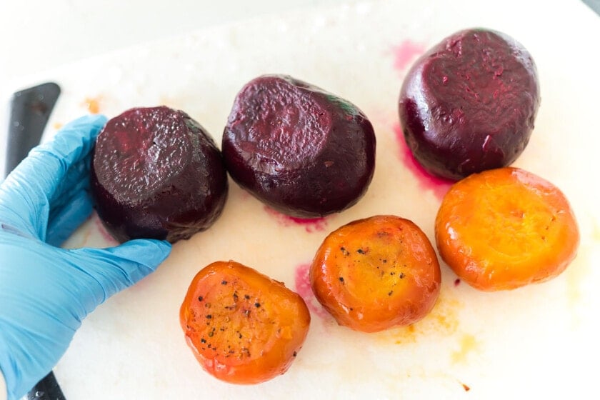 Roasted whole red and golden beets on a cutting board.