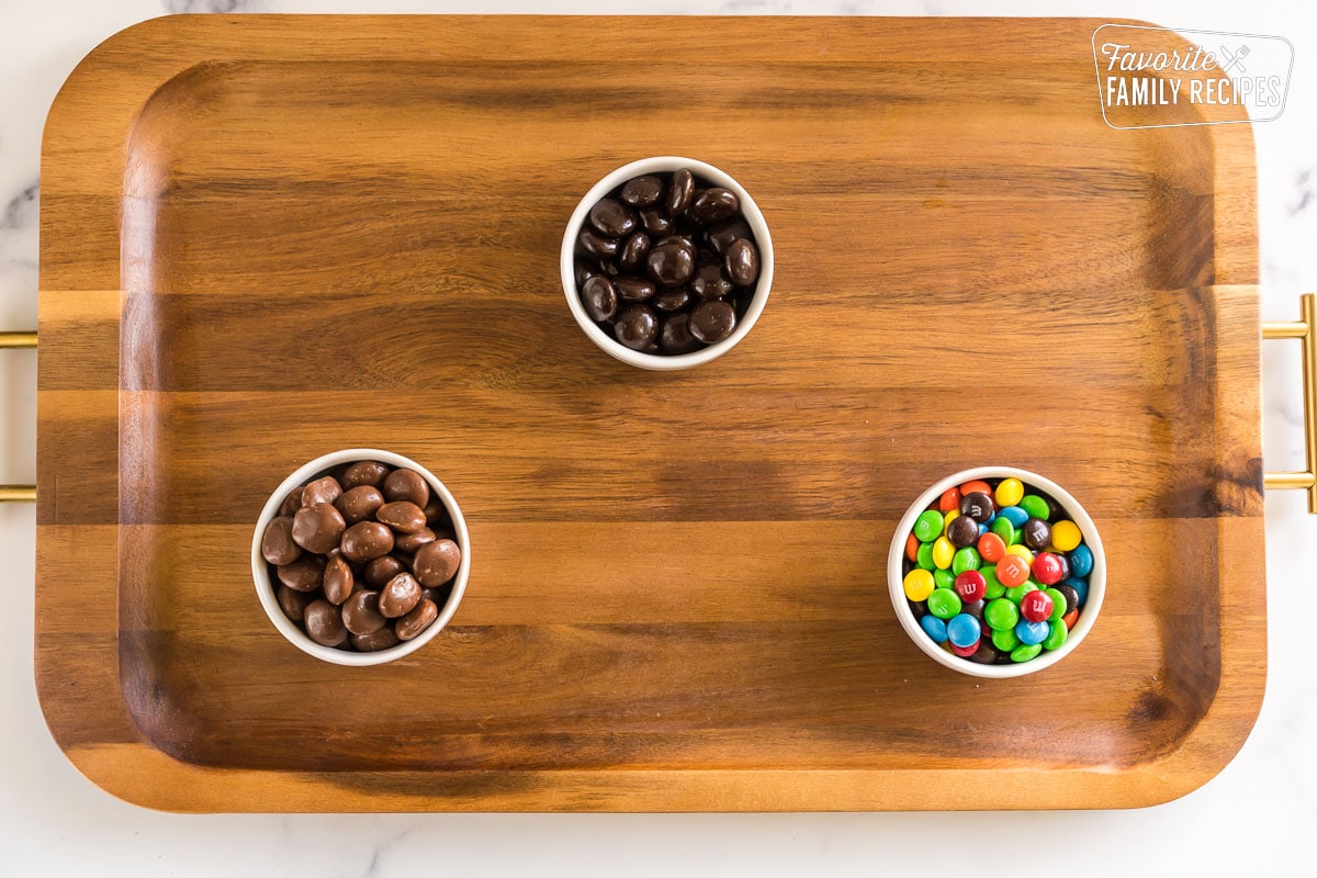 A board with three little bowls of candy