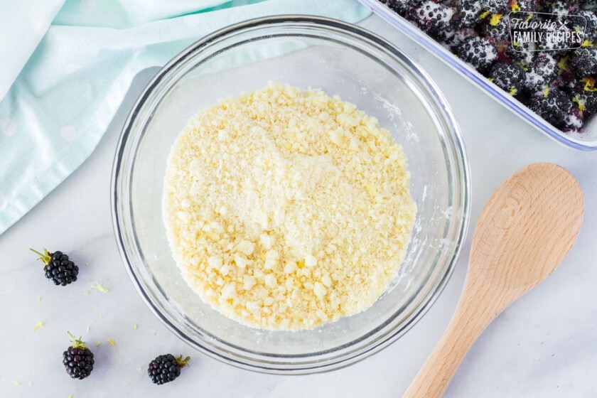 Mixing bowl with flour, sugar and egg crumble topping for Easy Blackberry Cobbler.