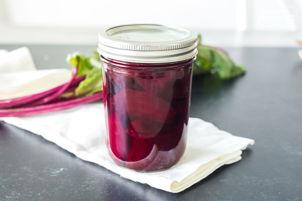 A clear jar of pickled beets with a lid.