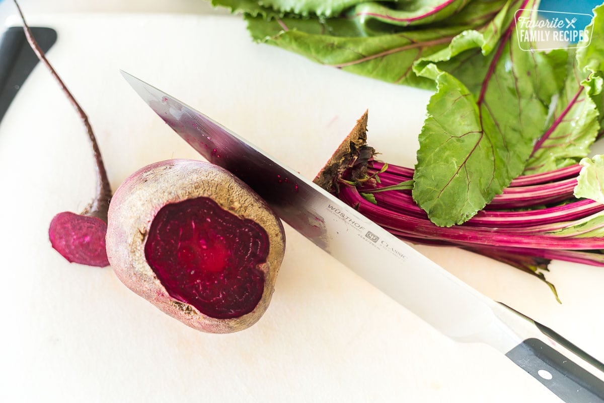 Learn the easiest way to oven roast beets and discover new ways of serving them! Our step-by-step guide will teach you everything you need to know about roasted beets. A fresh red beet on a cutting board with a knife.