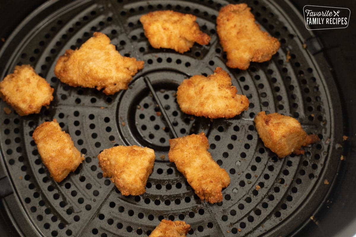 Cooked chicken nuggets in an air fryer basket.