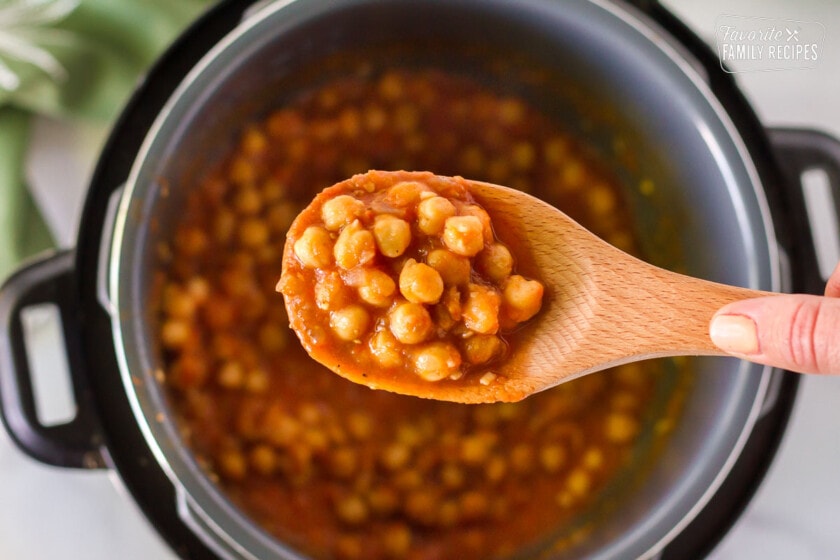 Close up of cooked Curried Chickpeas in a wooden spoon.