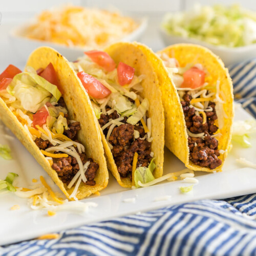 A white plate with three ground beef tacos.