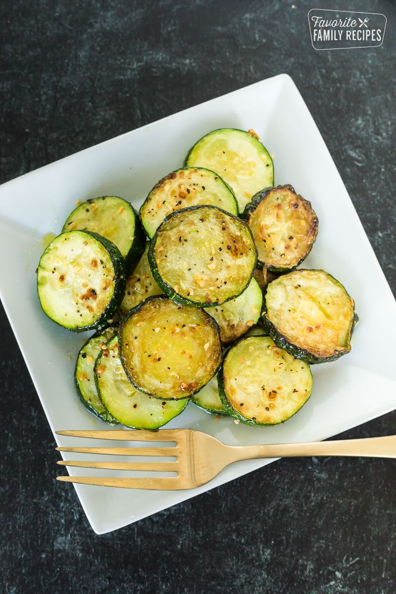 Sautéed zucchini on a plate with a gold fork.