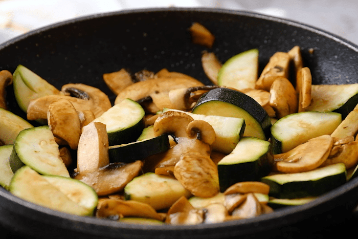 Mushrooms, zucchini, and soy sauce in a pan for Panda Express Mushroom Chicken.
