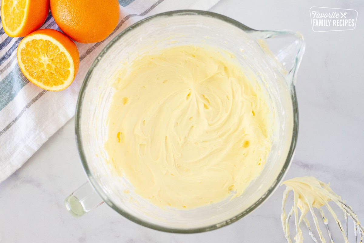 Mixing bowl of Orange Pancake filling. Whisk and oranges on the side.