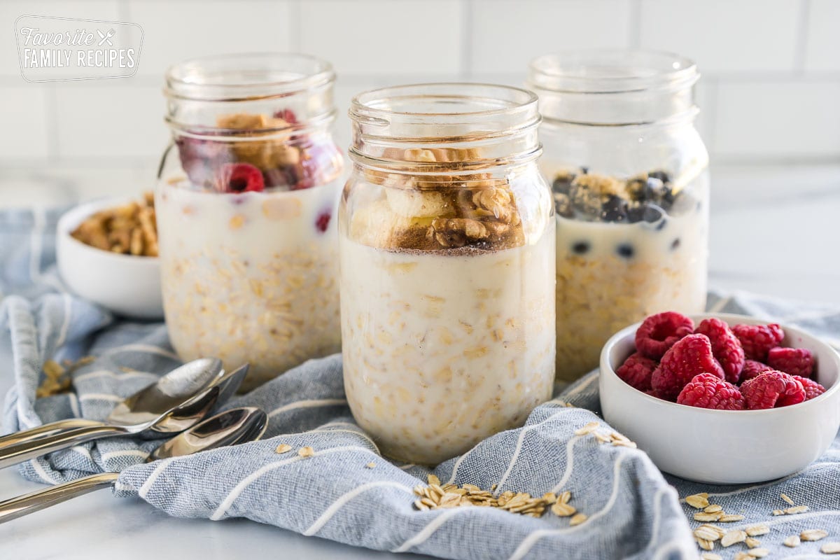 Three jars of oats with fruit in them. 