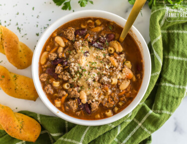 A bowl of pasta e fagioli soup topped with grated parmesan and parsley