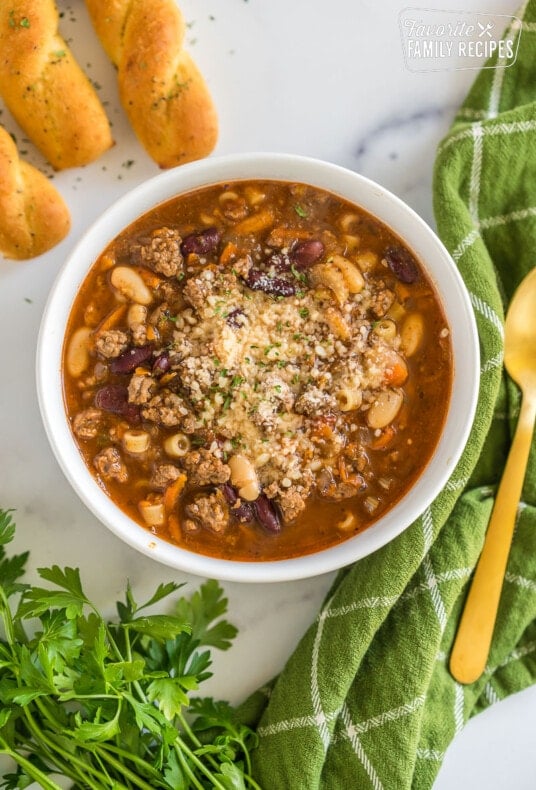 A bowl of pasta e fagioli soup topped with grated parmesan and parsley