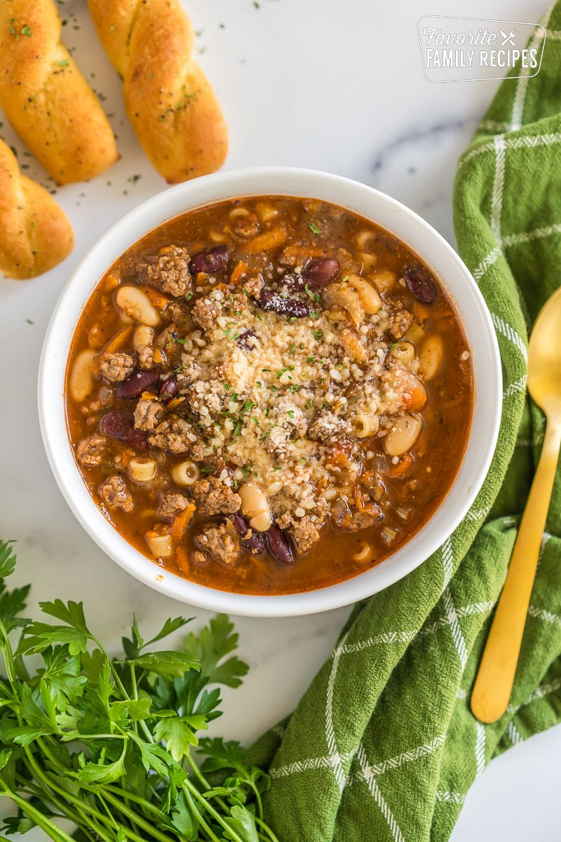 A bowl of pasta e fagioli soup topped with grated parmesan and parsley