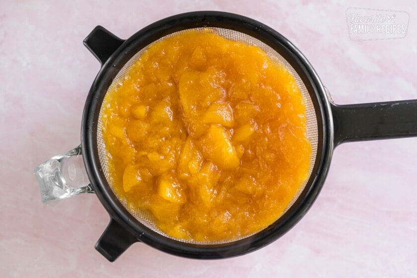 Peach syrup straining through a mesh colander