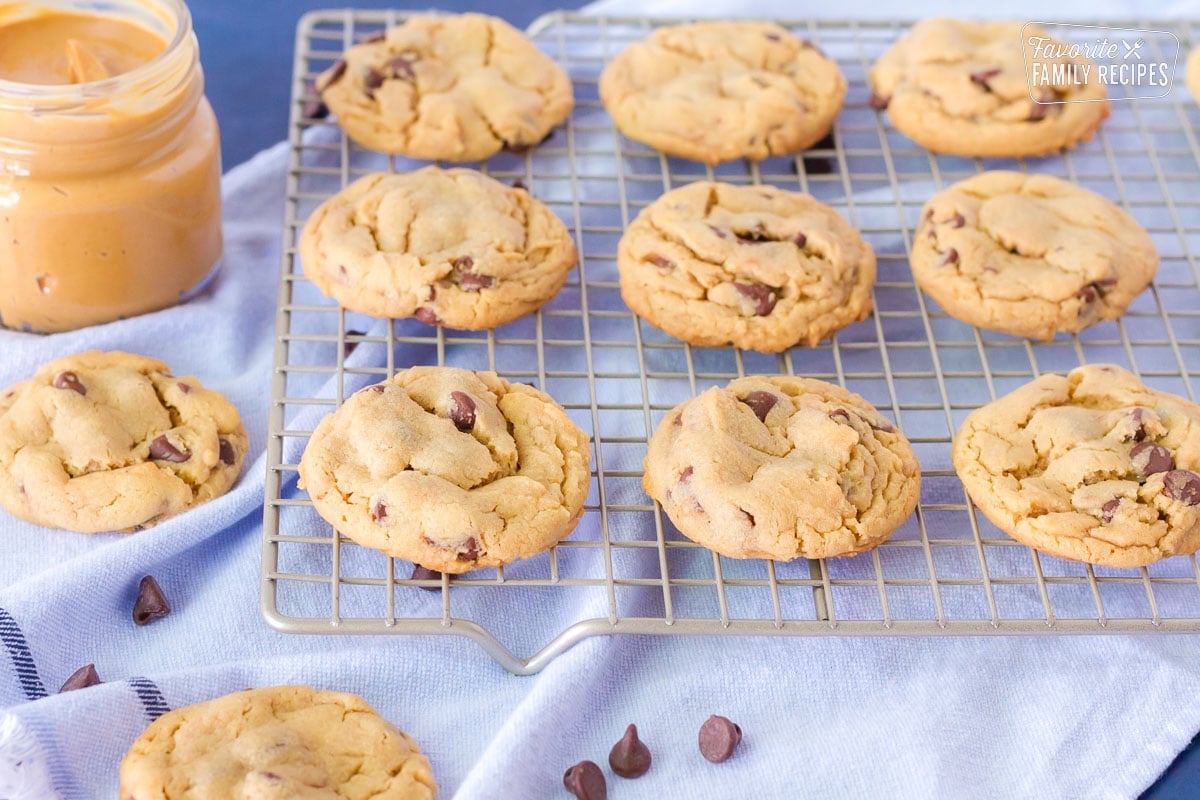 Cooling rack of Peanut Butter Chocolate Chip Cookies. Jar of peanut butter on the side.