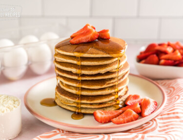 A stack of protein pancakes with strawberries and syrup