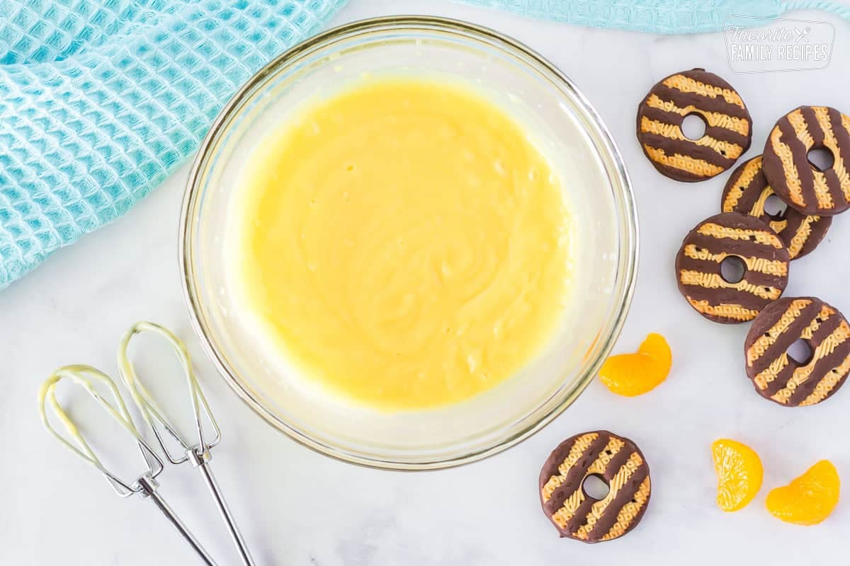 Bowl of vanilla pudding mix with beaters on the side. Fudge Striped cookies and mandarin oranges on the side.