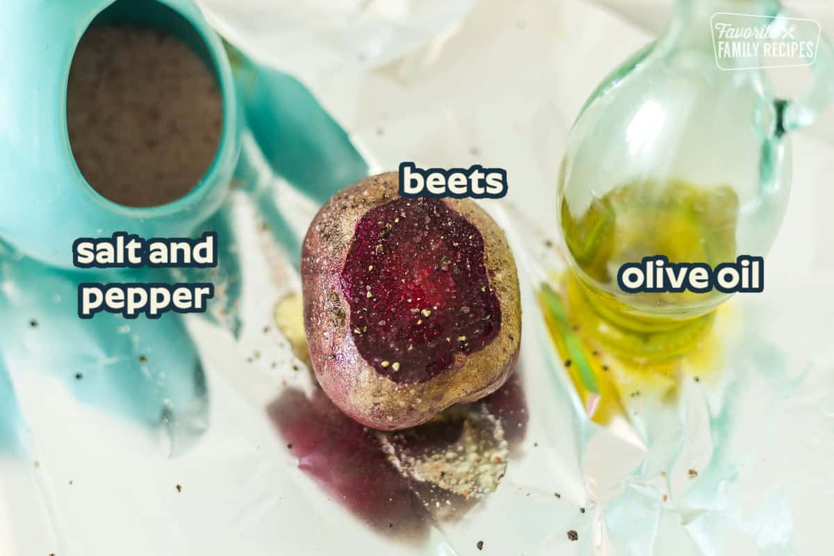 Ingredients to roast beets including a red beet, olive oil, and salt and pepper on a tray of foil.