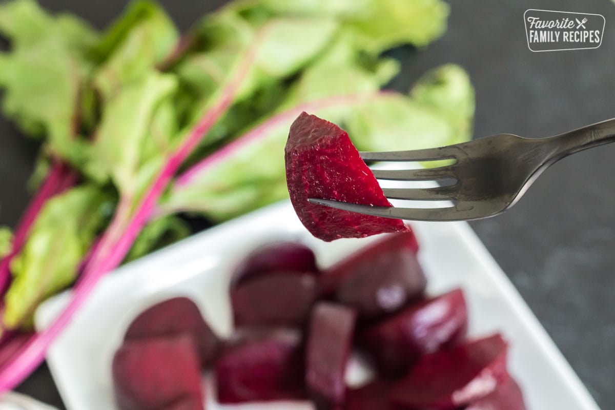 Learn the easiest way to oven roast beets and discover new ways of serving them! Our step-by-step guide will teach you everything you need to know about roasted beets. A roasted red beet slice on a fork.