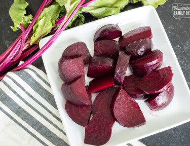 Sliced roasted beets on a white plate.
