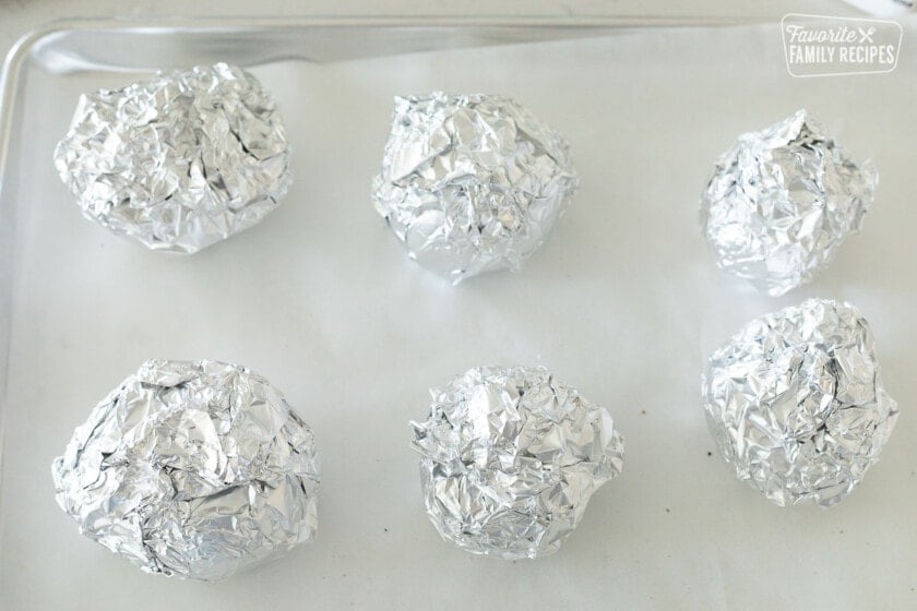 Roasted beets wrapped in foil on a baking sheet.