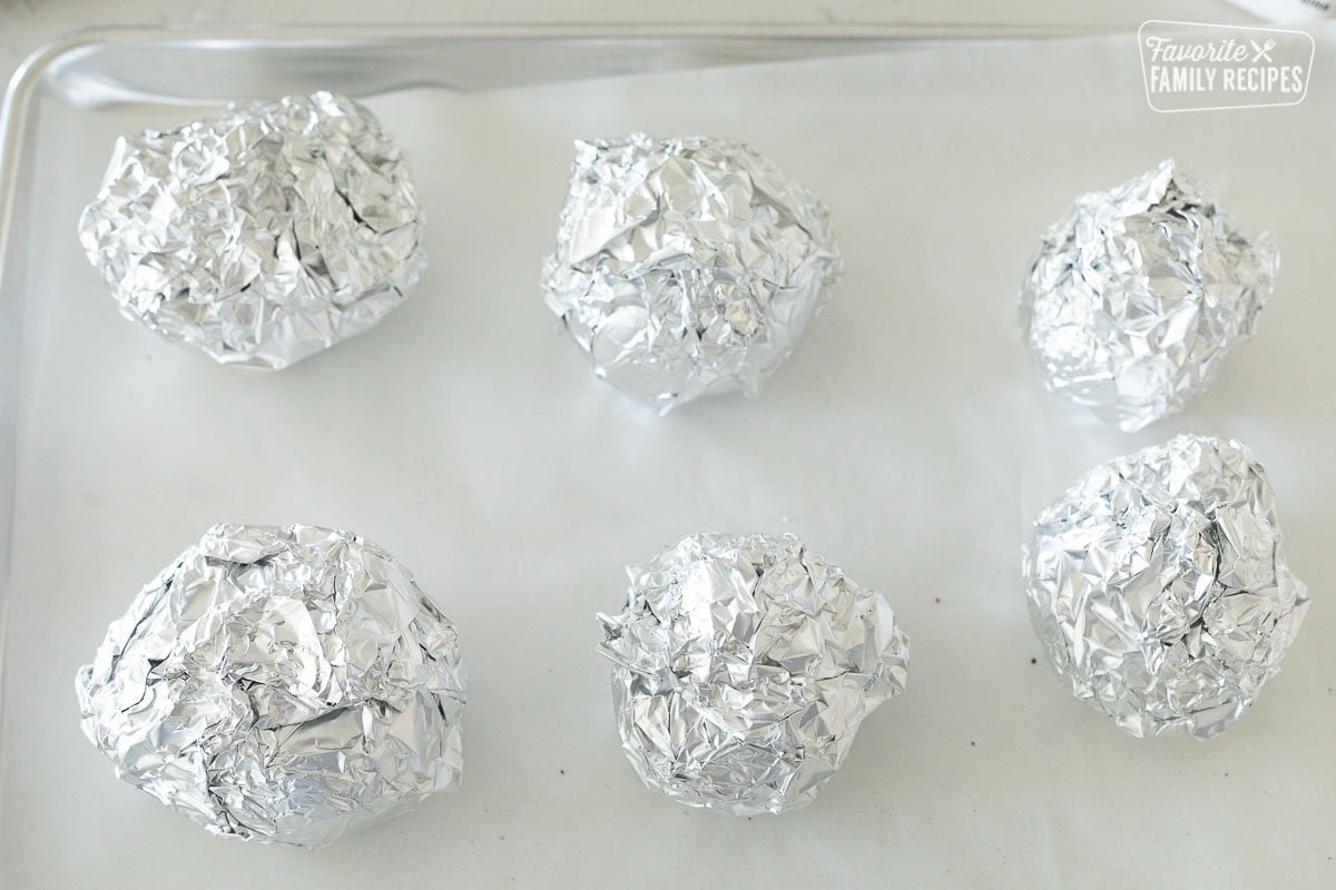 Roasted beets wrapped in foil on a baking sheet.