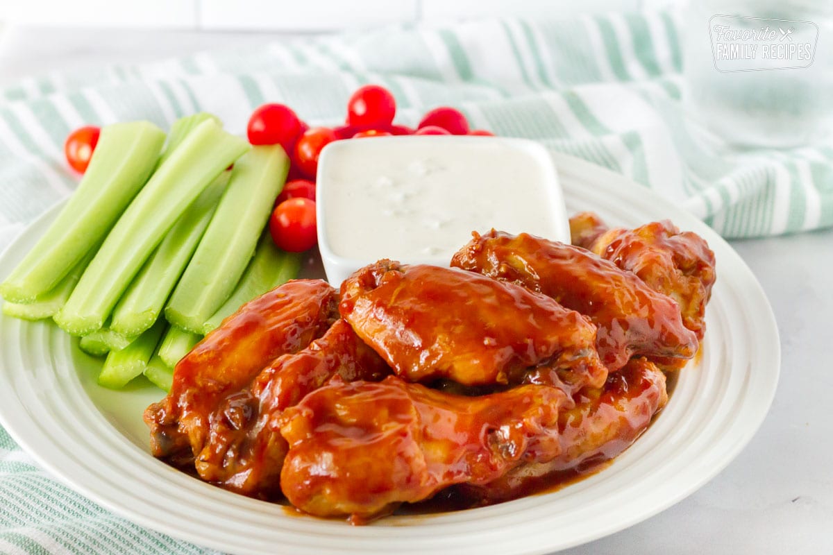 Side View of a plate with Hot Wings and Blue Cheese Dressing. Celery and tomatoes on the side.